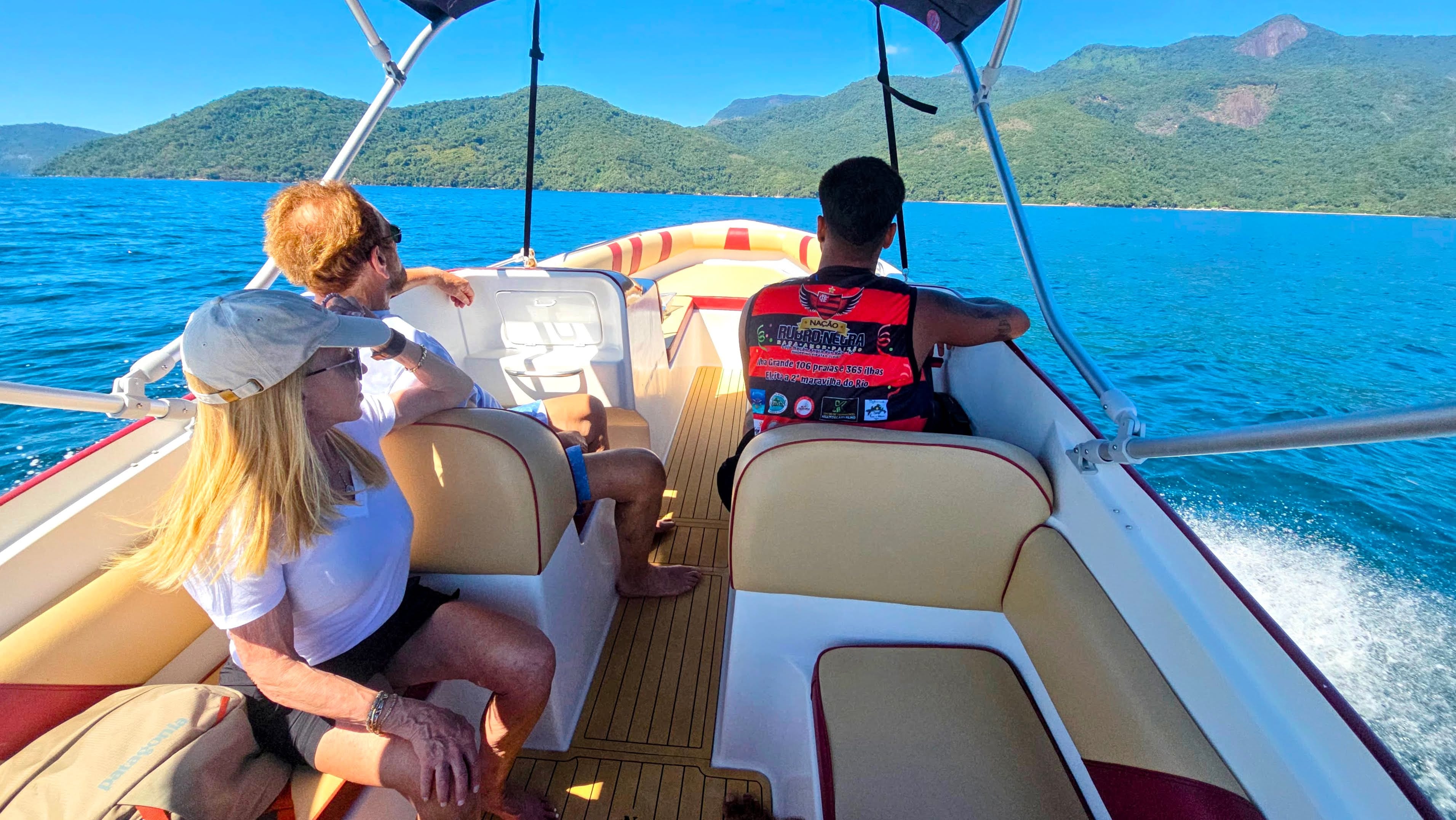 Guests sitting on a private speedboat cruising along the coastline of Ilha Grande.