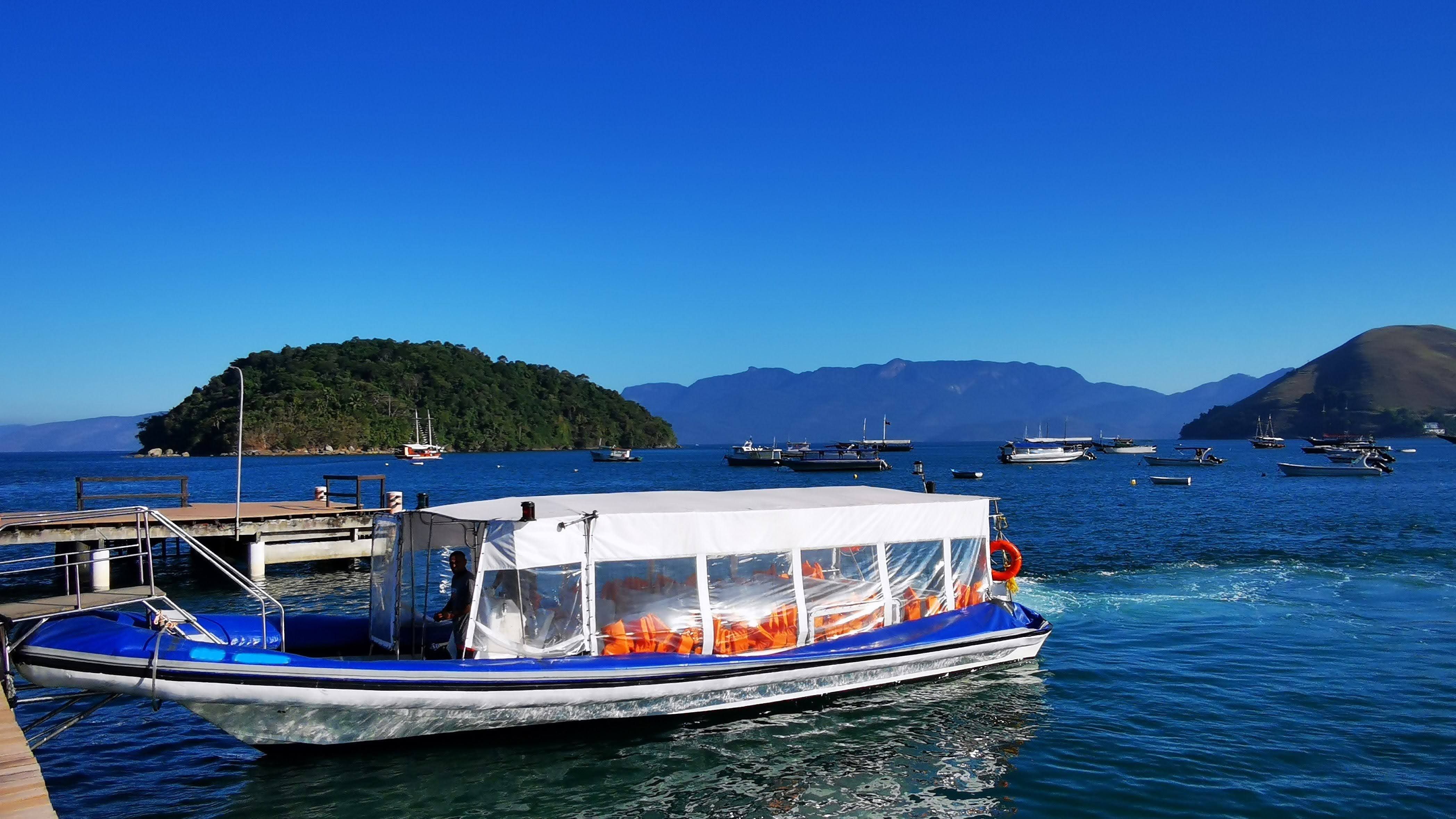 Lancha de passageiros chegando ao píer em Conceição de Jacareí, com a Ilha Grande e a Mata Atlântica visíveis do outro lado da baía, Costa Ver