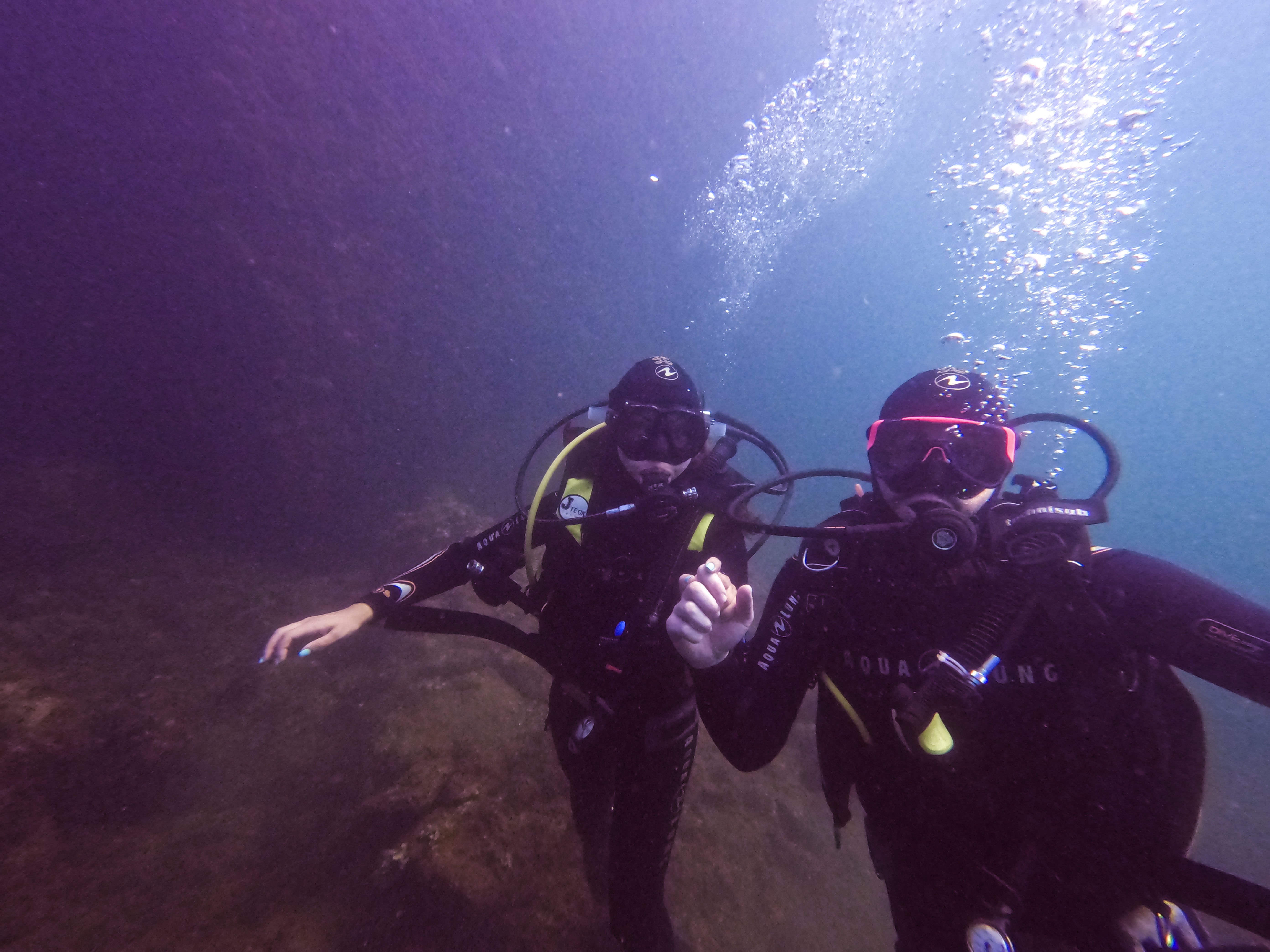 Couple of divers underwater posing for photo holding hands.