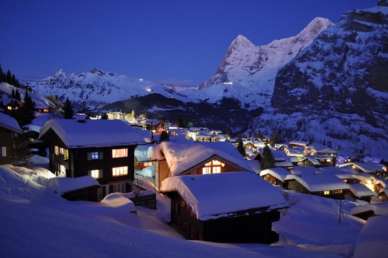 Mürren à noite, com os chalés iluminados na neve e o Eiger ao fundo.