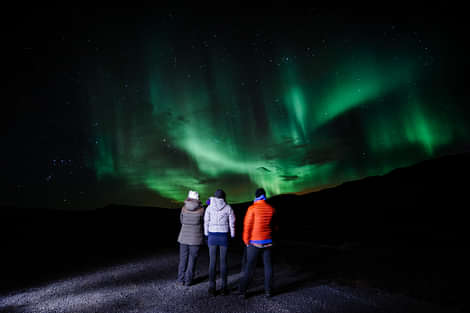 A group of people enjoying the Northern lights during Northern lights jeep tour Iceland