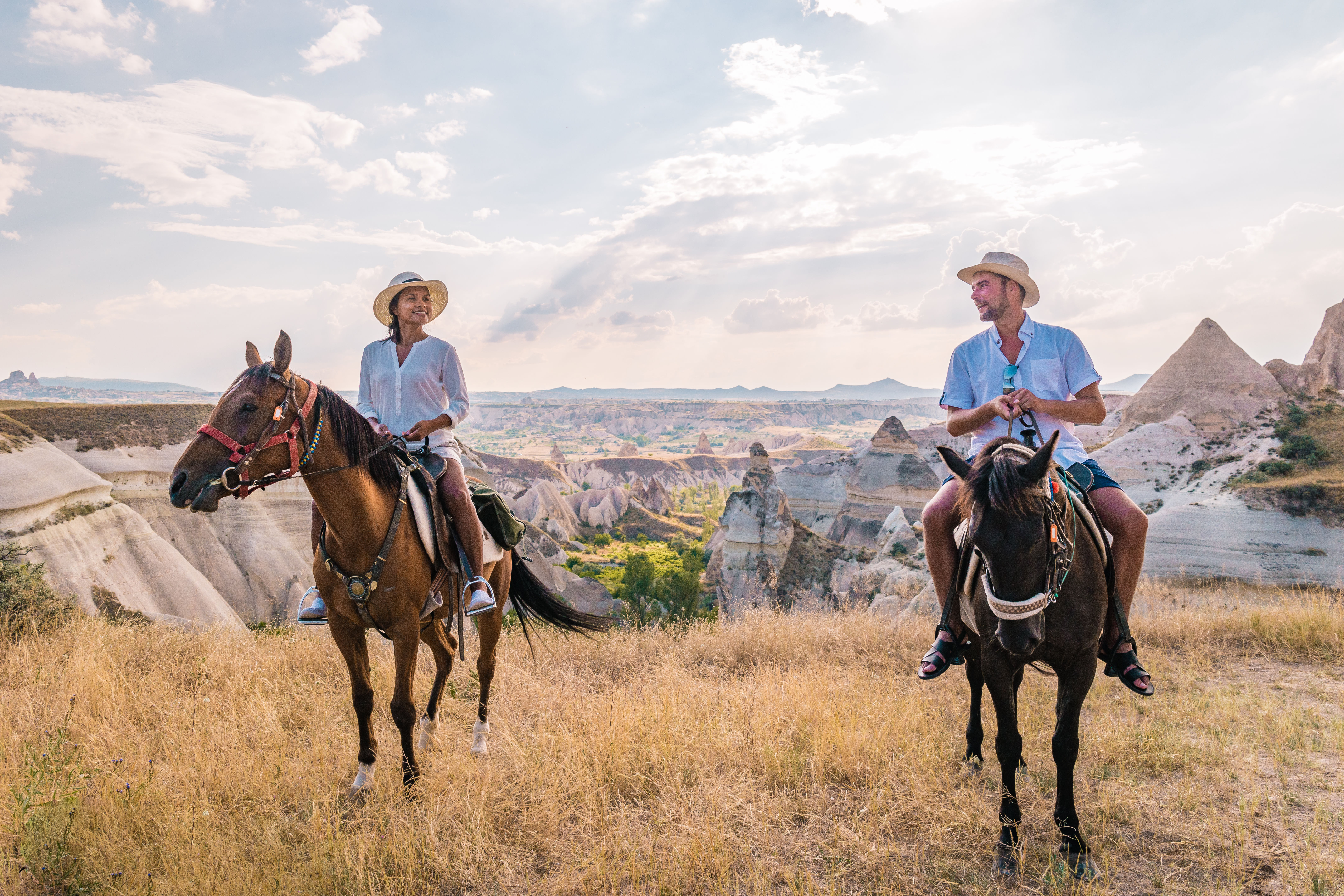 “A person riding a horse along a trail surrounded by the rocky valleys and natural scenery of Cappadocia.”