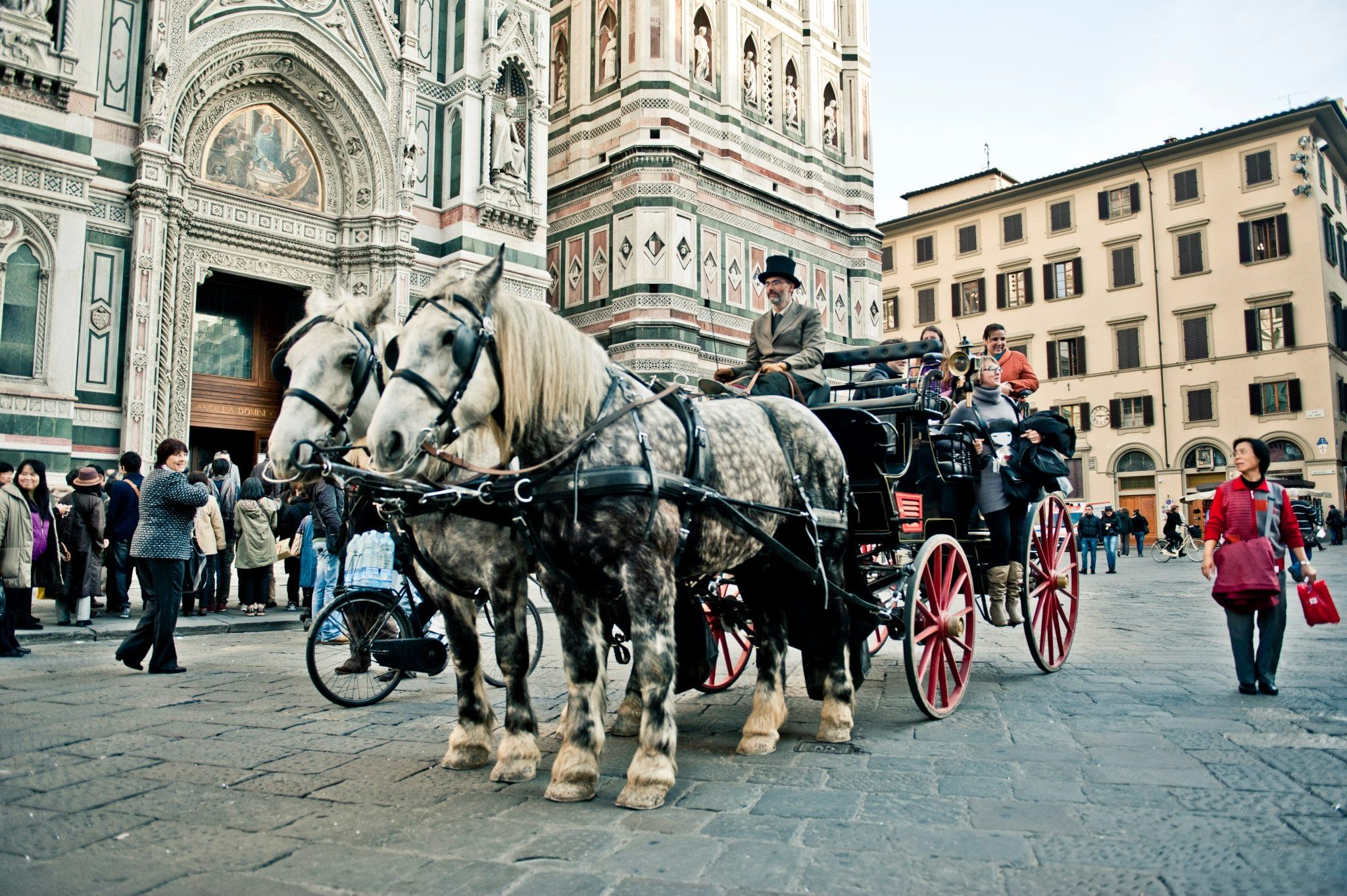 View of a horse-drawn carriage and its coachman in Duomo Square; on the background you can see the Cathedral and the Belltower