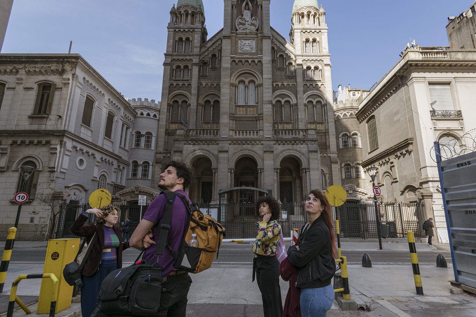 A tour guide and three guests look up by the Basilica of the holy sacrament