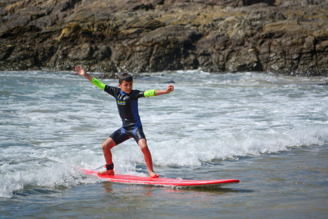 Child surfing a small wave during a beginner surf lesson at Cerritos Beach
