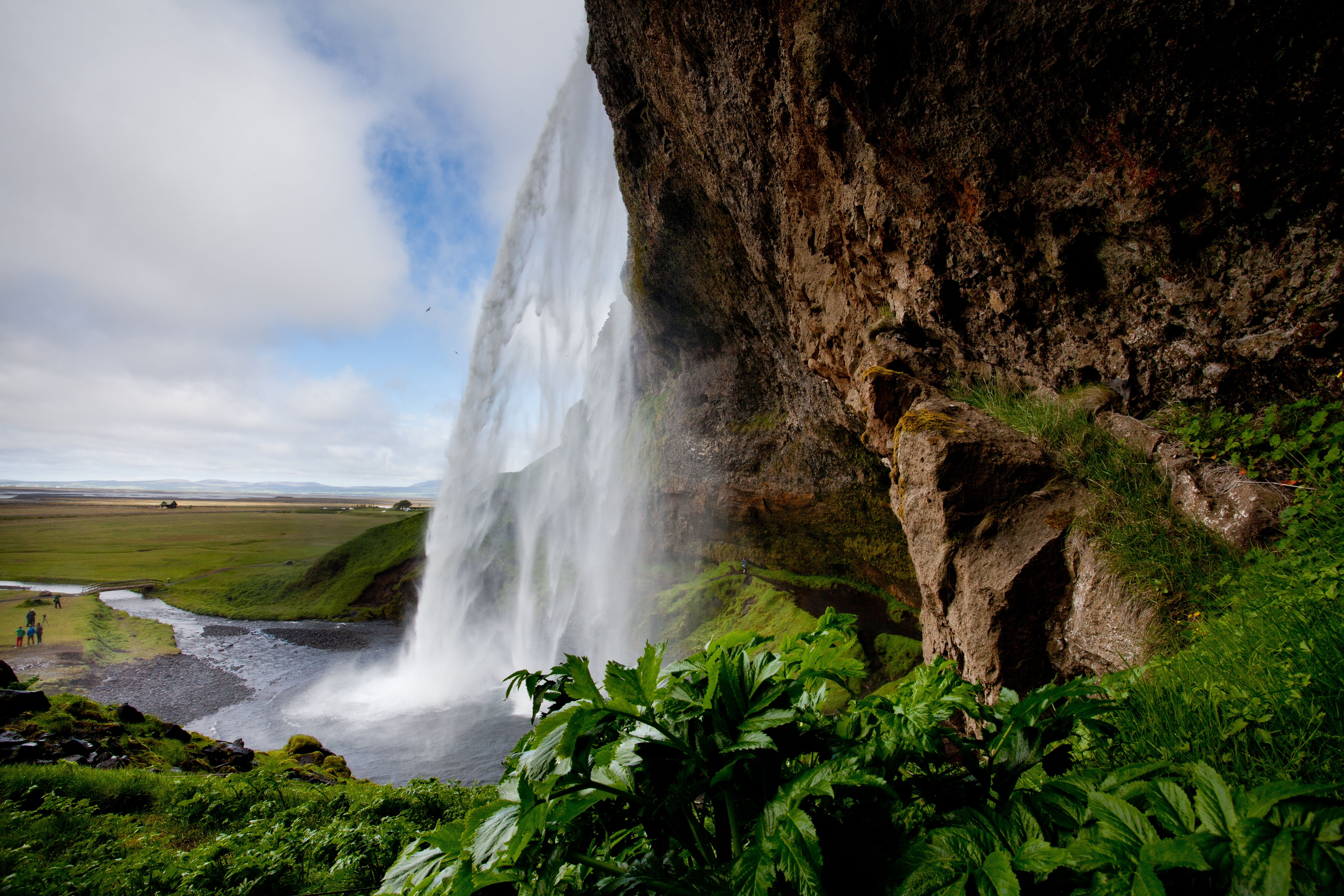 Beneath Seljalandsfoss Waterfall to the right of the waterfall.