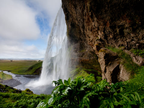 Beneath Seljalandsfoss Waterfall to the right of the waterfall.