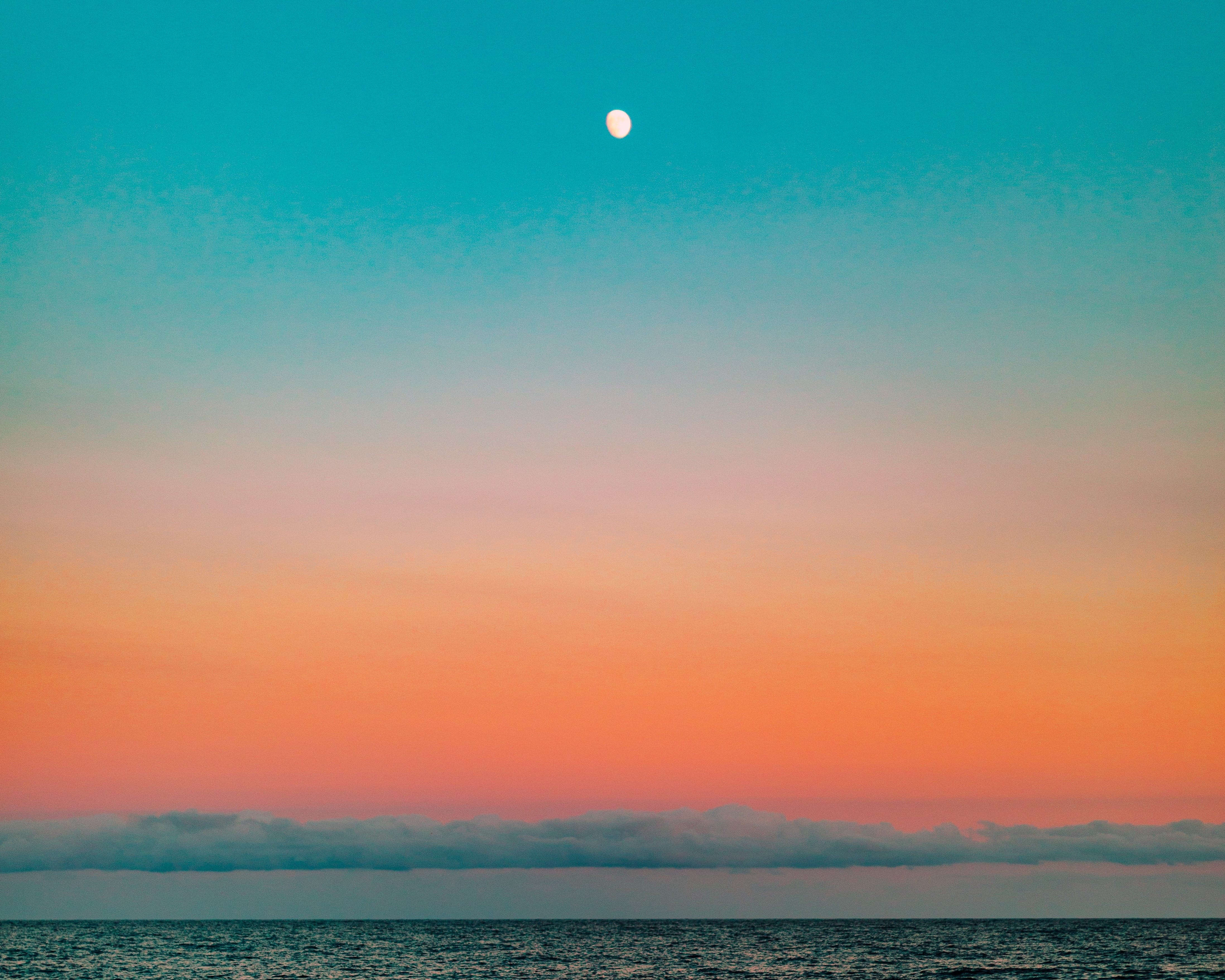 Sky that goes from top to bottom, to the horizon of the sea, cyan, light blue, pink, orange to an intense reddish color.
