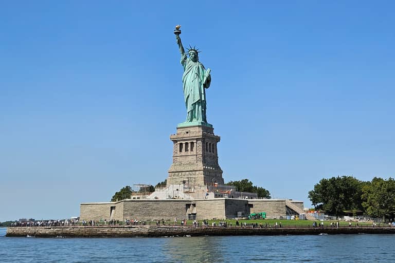Statue of Liberty standing on Liberty Island with pedestal and grounds visible from boat tour