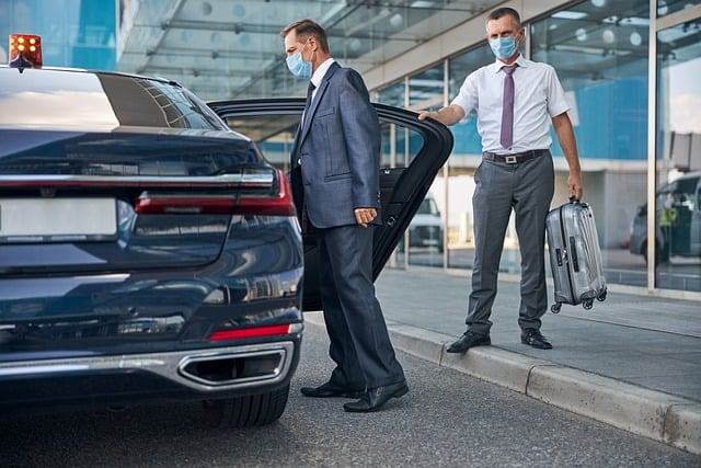 Driver assisting a passenger with luggage and guiding them to their vehicle for a Piraeus Port transfer.