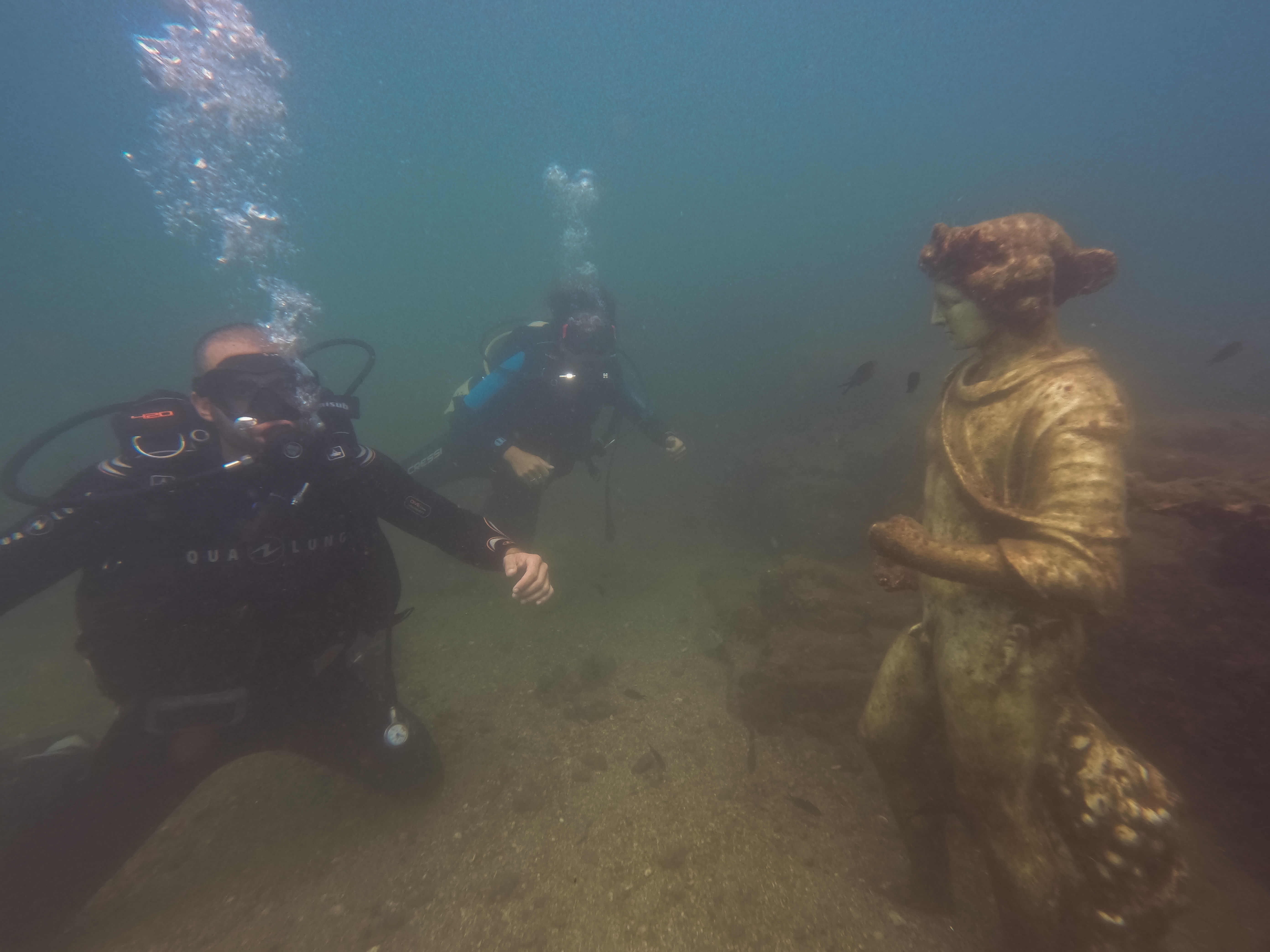 Divers posing in front of the statue of the god Dionysus of the 