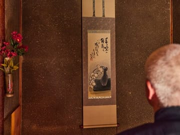 In a simple and narrow Japanese-style room, only seasonal flowers and hanging scrolls are displayed there modestly, nothing else.
