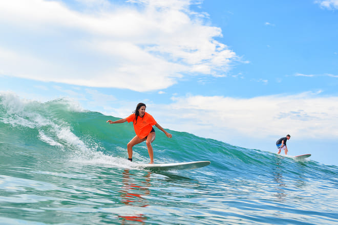 Woman surfing a green wave at Cerritos in Los Cabos during a surf lesson