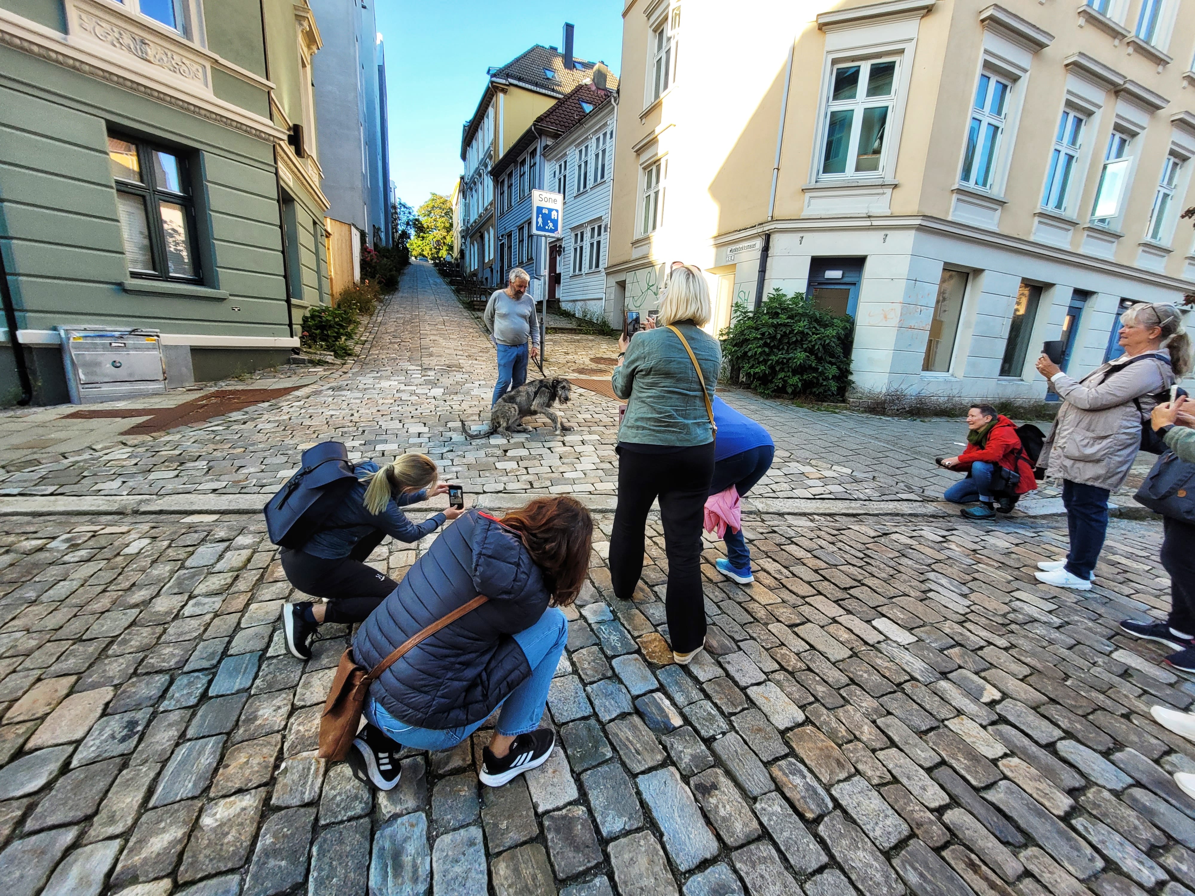 Participants photographing a local resident with a dog during the Bergen Photowalk.