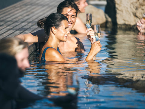 Guests enjoying a glass of wine in the Hvammsvik Hot Springs