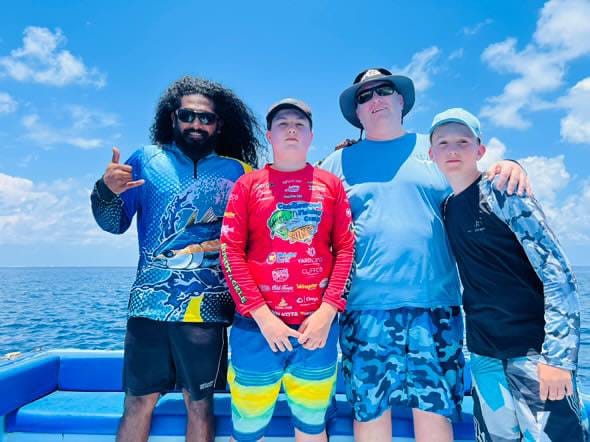 A local expert guide from Ocean Adventurers Fuvahmulah posing with a family, including children, after a successful fishing trip