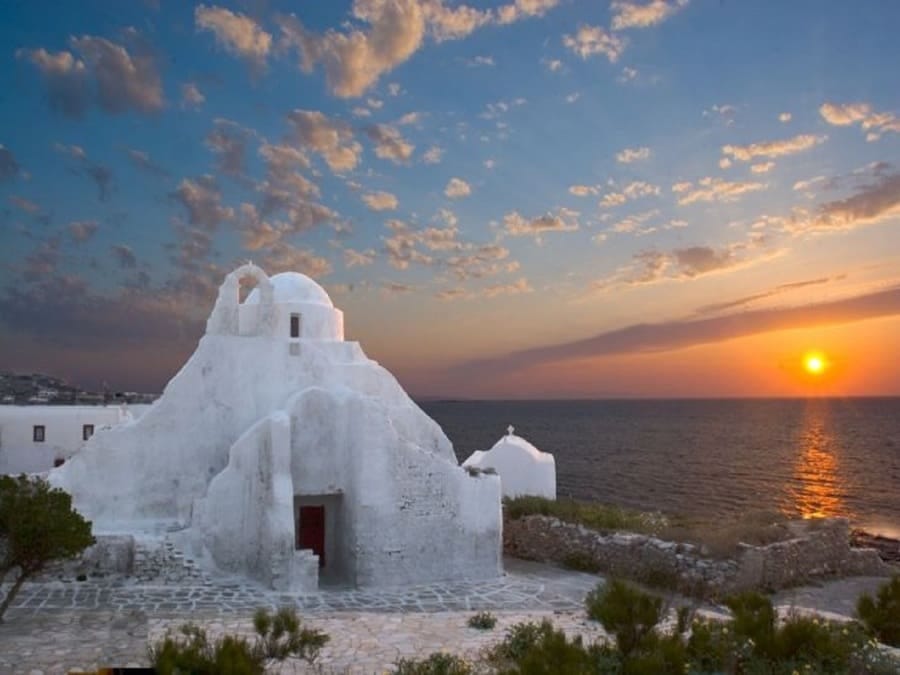 Weiß getünchtes Haus auf Mykonos bei Sonnenuntergang mit warmem goldenem Licht über der kykladischen Architektur