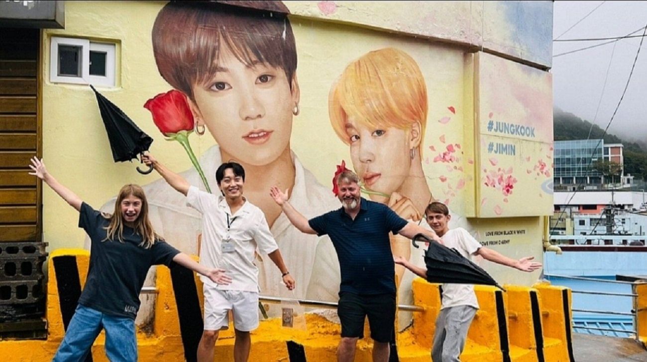 Tourists standing in front of BTS and K-pop themed murals at Gamcheon Culture Village.