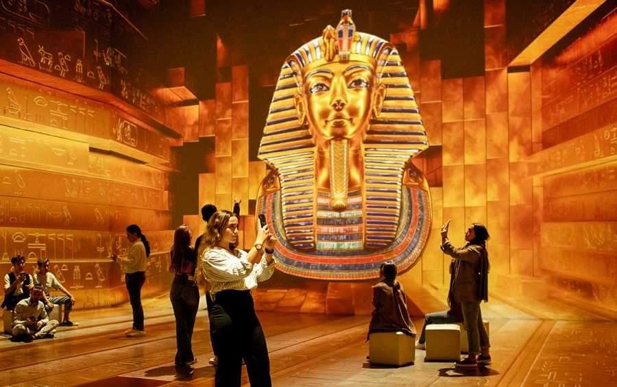 Grand Egyptian Museum exterior with visitors entering the modern glass building near the Giza Plateau.