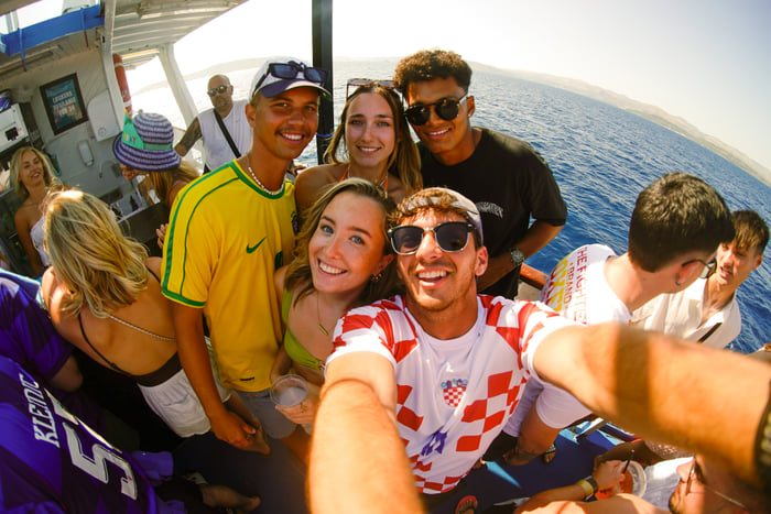 A group selfie on the boat with the coast behind