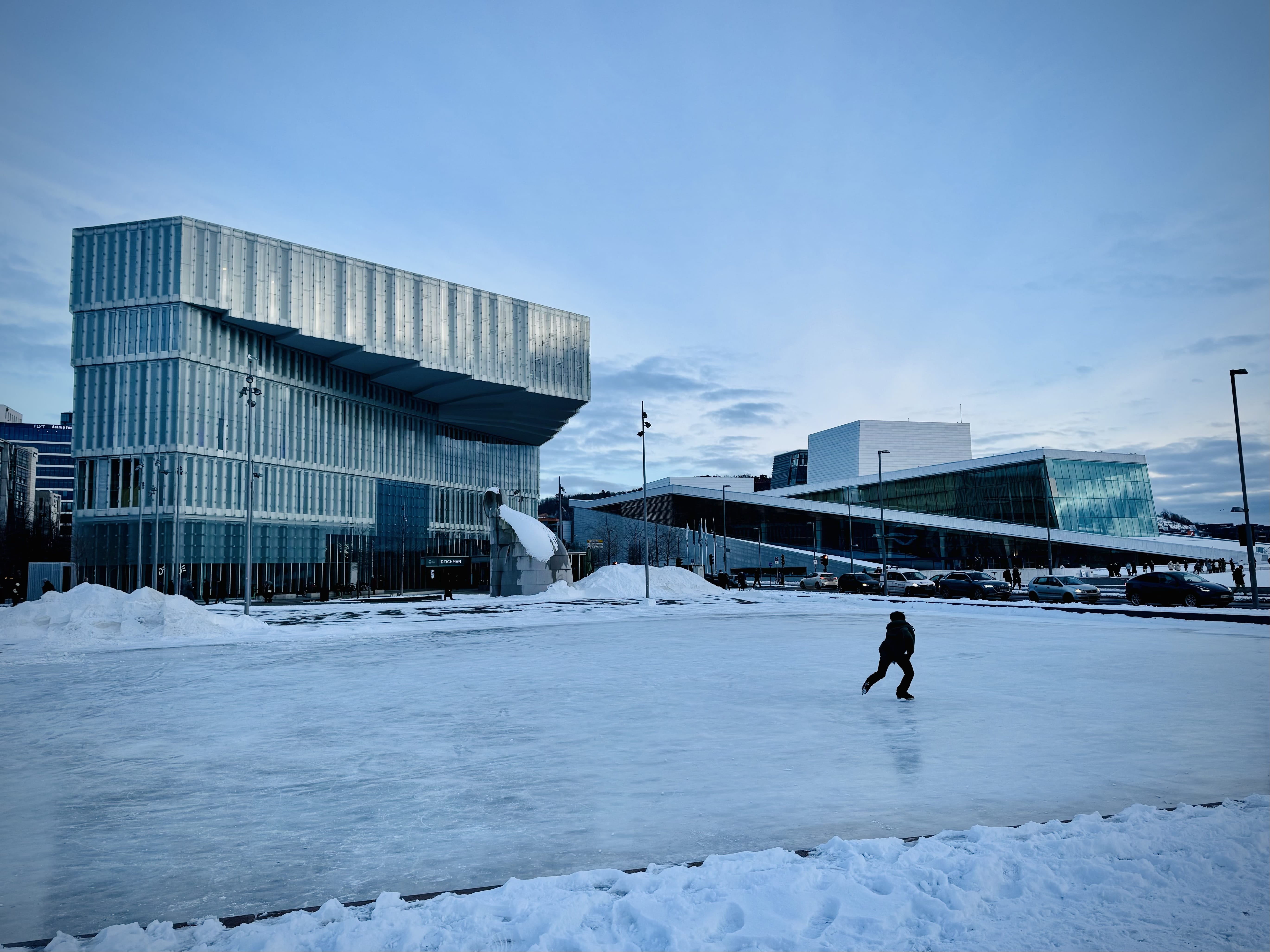 Ice skater skating. Deichman Library and the Opera are in the background