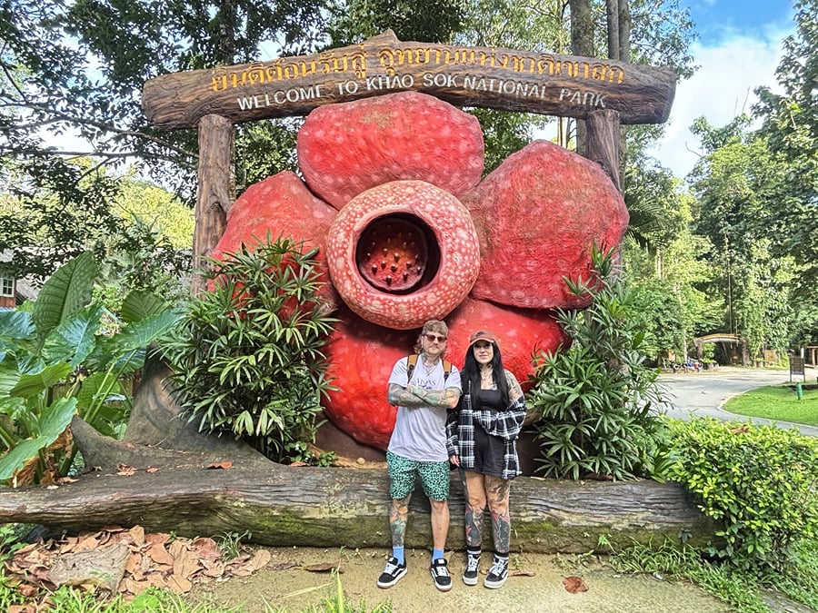 Two guests in front of the Rafflesia flower sign at the Khao Sok National Park entrance