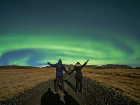 A couple standing underneath the auroras in Iceland.