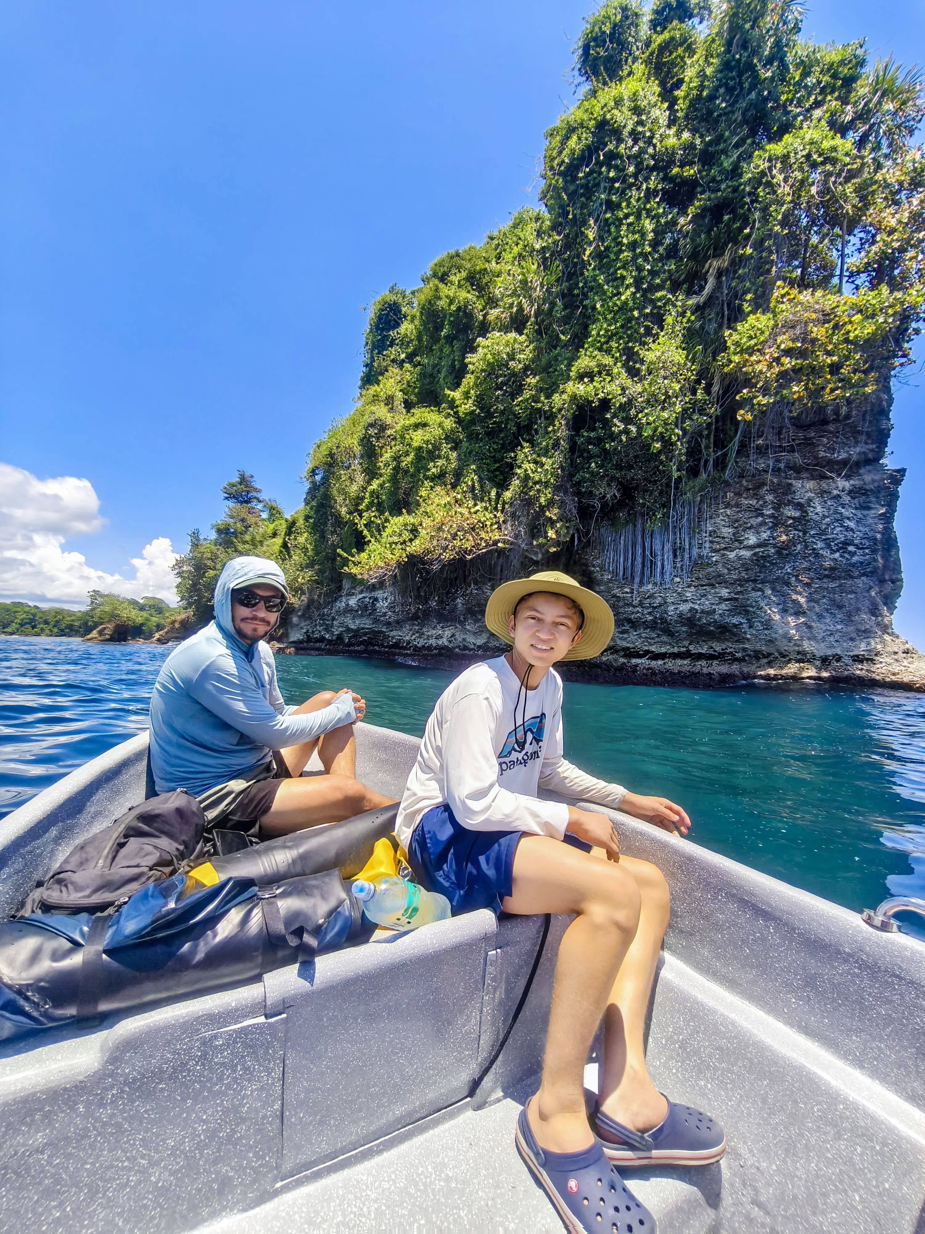 Travelers exploring the scenic cliffs and rainforest coastline of Punta Mona during a dolphin watching boat tour from Manzanillo, Costa Rica