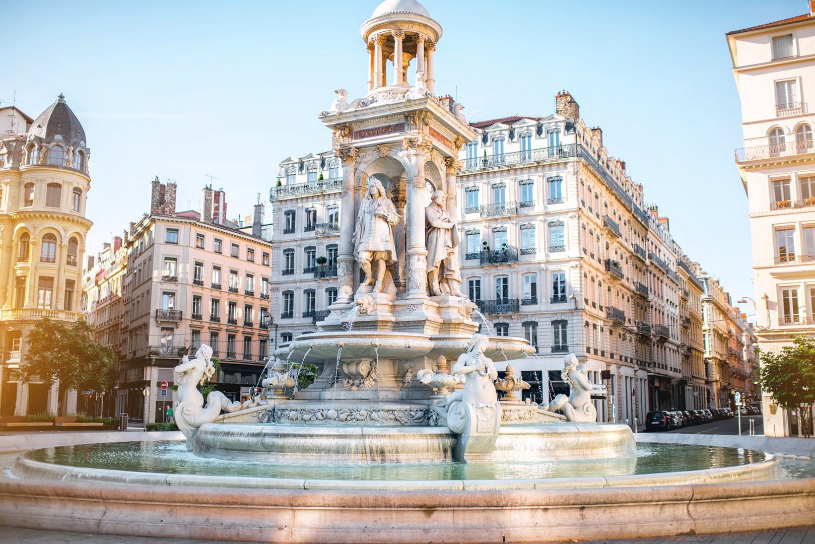 The ornate Fontaine des Jacobins in Lyon, featuring sculpted figures and water features, set against a backdrop of elegant Haussmann-style b