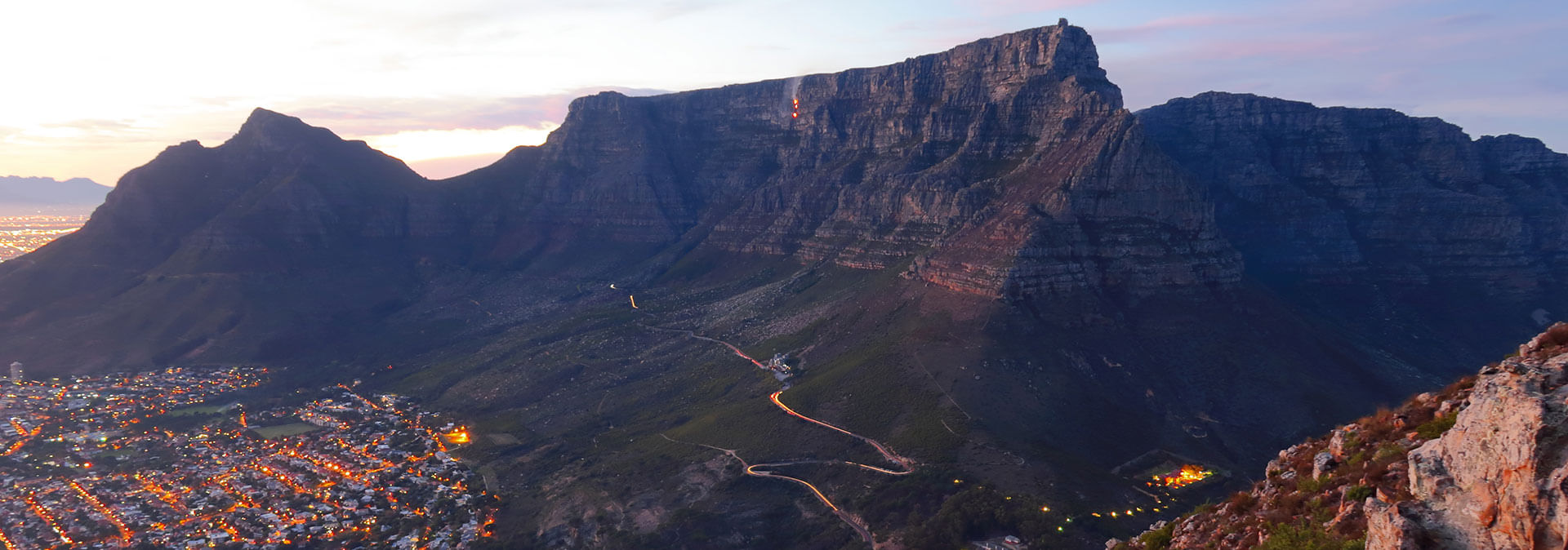 Majestic Table Mountain at twilight with Cape Town city lights below.