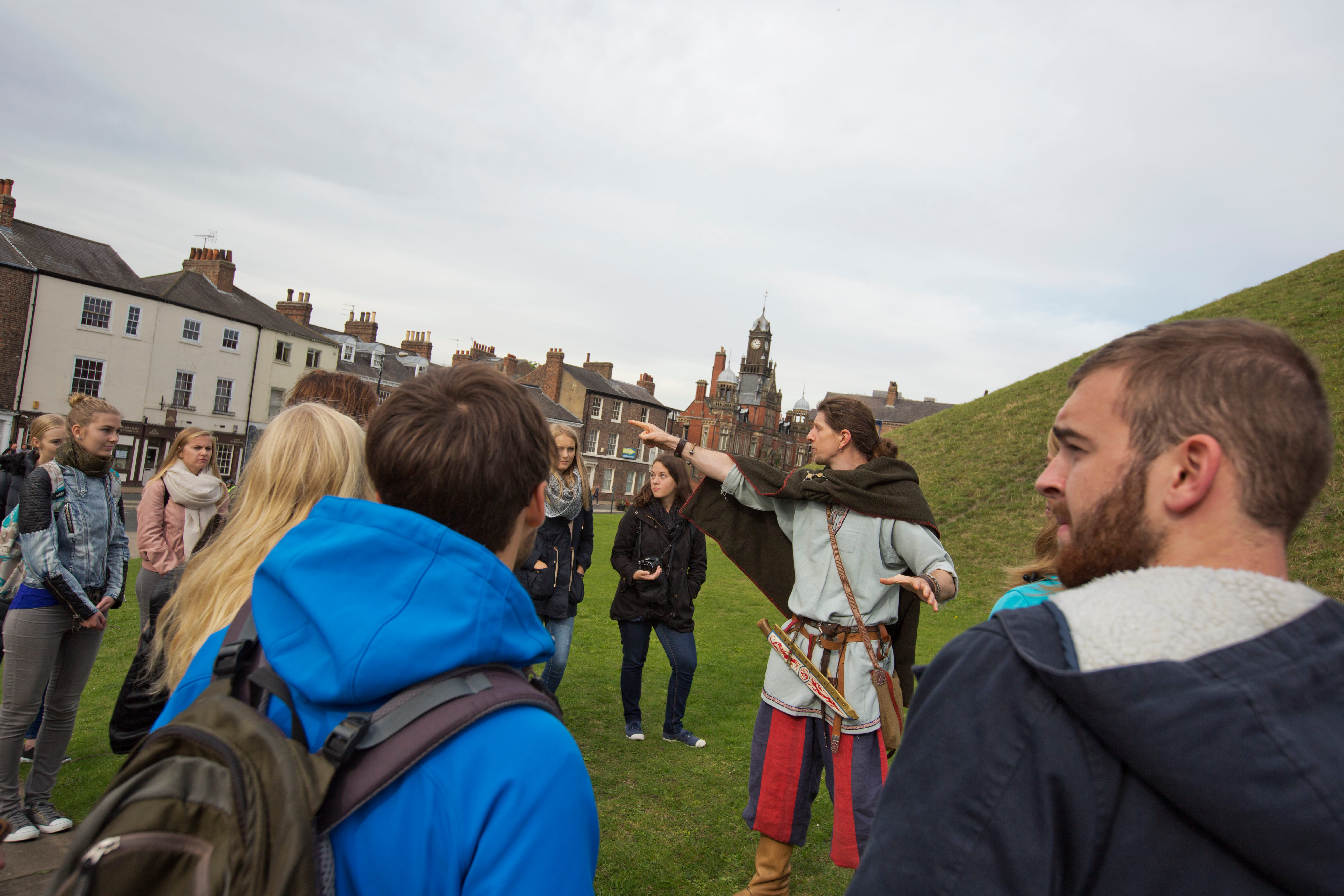 A viking tour guide with a group of international students, at Clifford's Tower, York. He is pointing towards the River Ouse (not pictured).