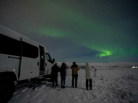 People standing beside of a Super Jeep watching the Aurora.