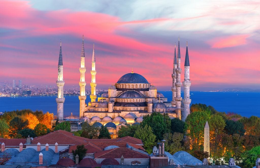 Sunset over Istanbul — a glowing skyline with domes and minarets in silhouette.