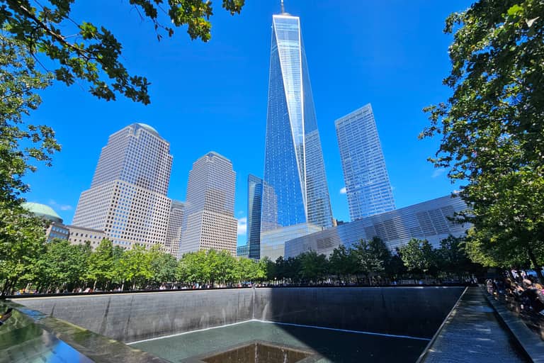 9/11 Memorial reflecting pool with One World Trade Center and Manhattan skyline