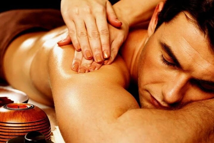 Close-up of a professional massage therapist's hands performing a back massage on a man.