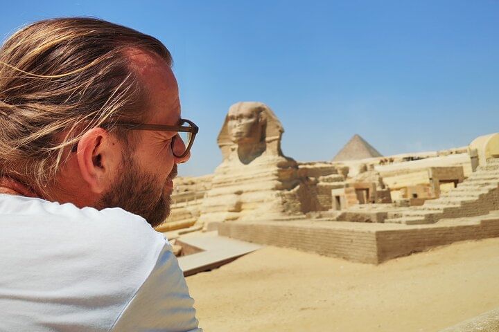 Tourist admiring the Great Sphinx of Giza under the clear sky.