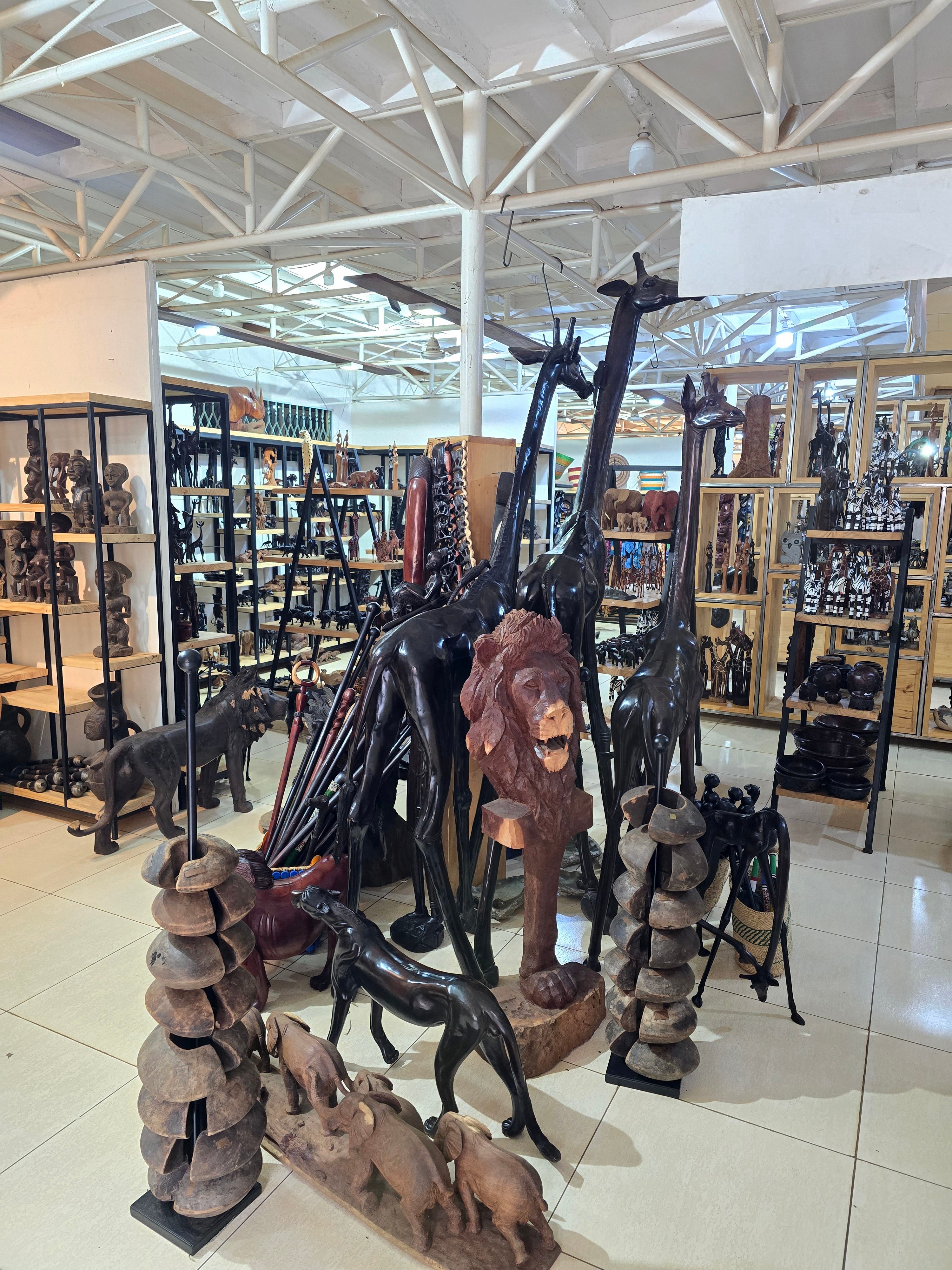 Impressive life-sized handcrafted wooden sculptures of giraffes and a lion featured inside an African souvenir gallery.