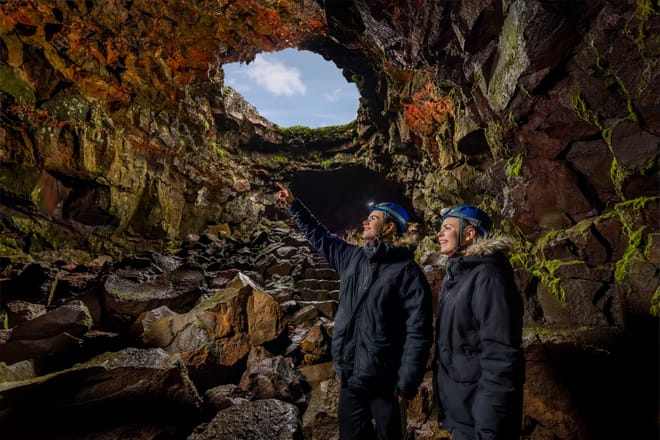 People standing inside a lava cave looking toward a natural opening above