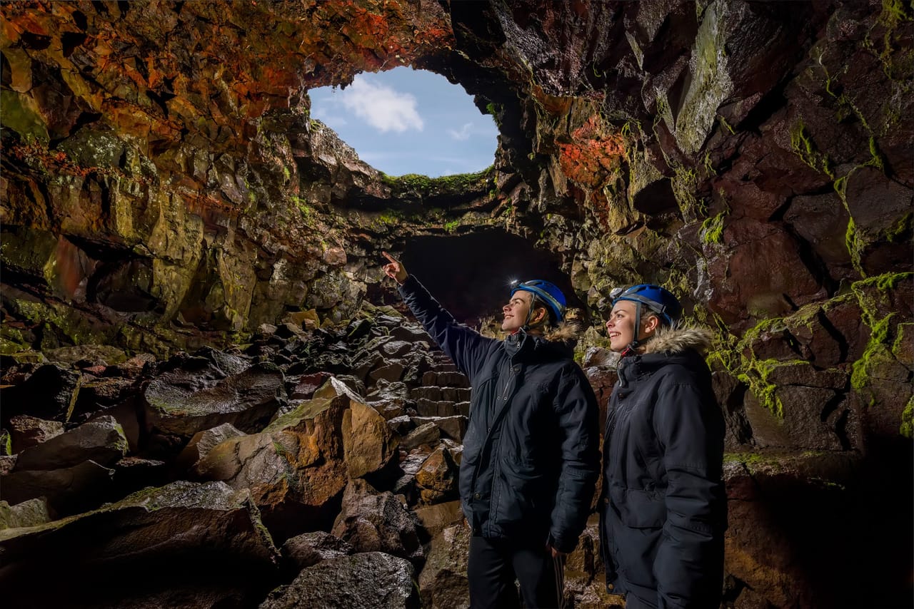 People standing inside a lava cave looking toward a natural opening above