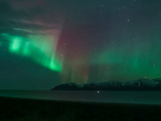 The auroras flicker like ethereal flames, illuminating the vastness of the winter sky.