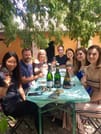 Guests are sitting around a table with Champagne glasses in their hands and smiling and toasting