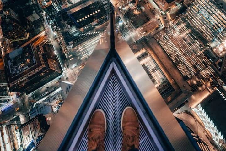 Person's feet dangling from Edge Observation Deck high above Manhattan buildings