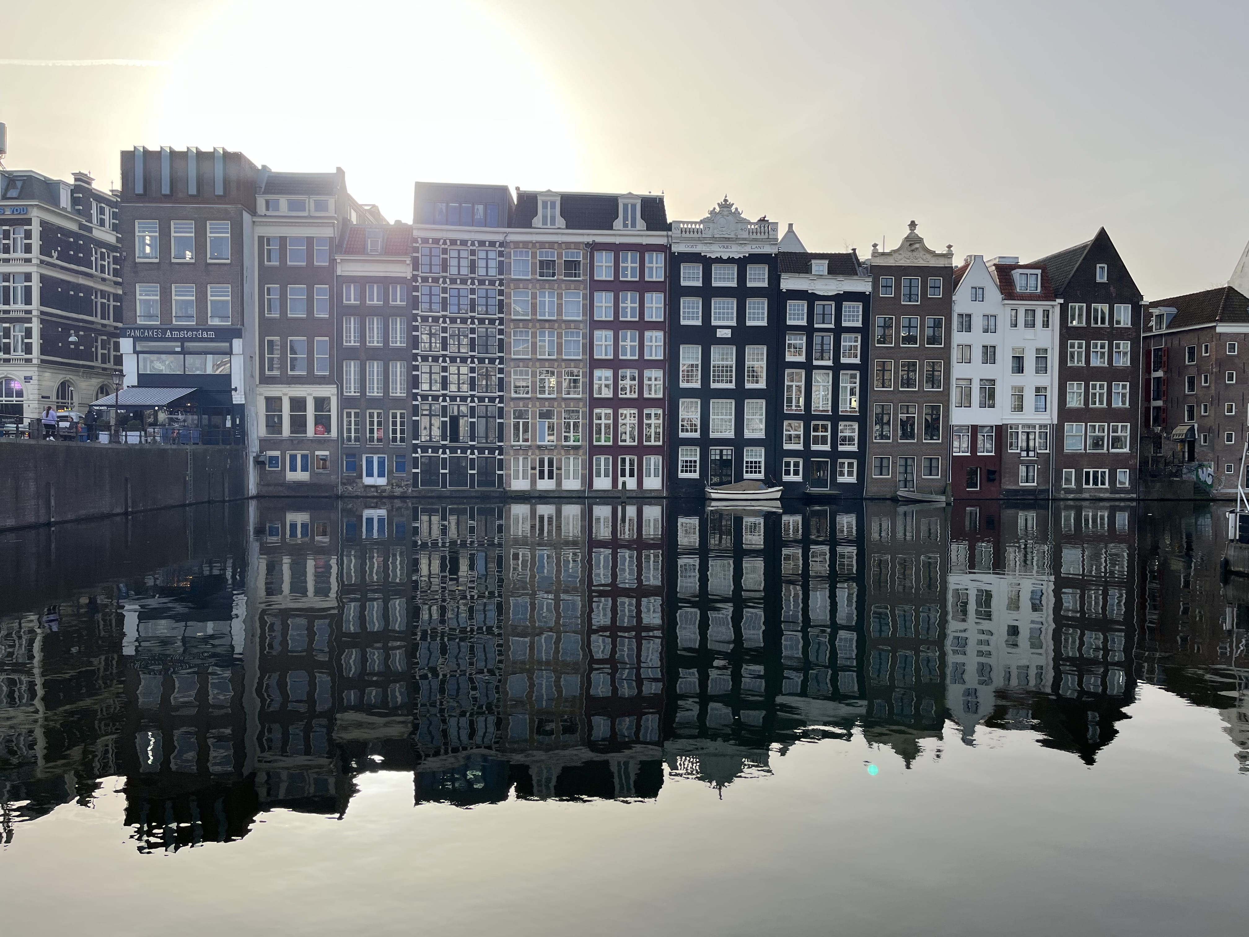Reflection of traditional Amsterdam canal houses in calm water during early morning light