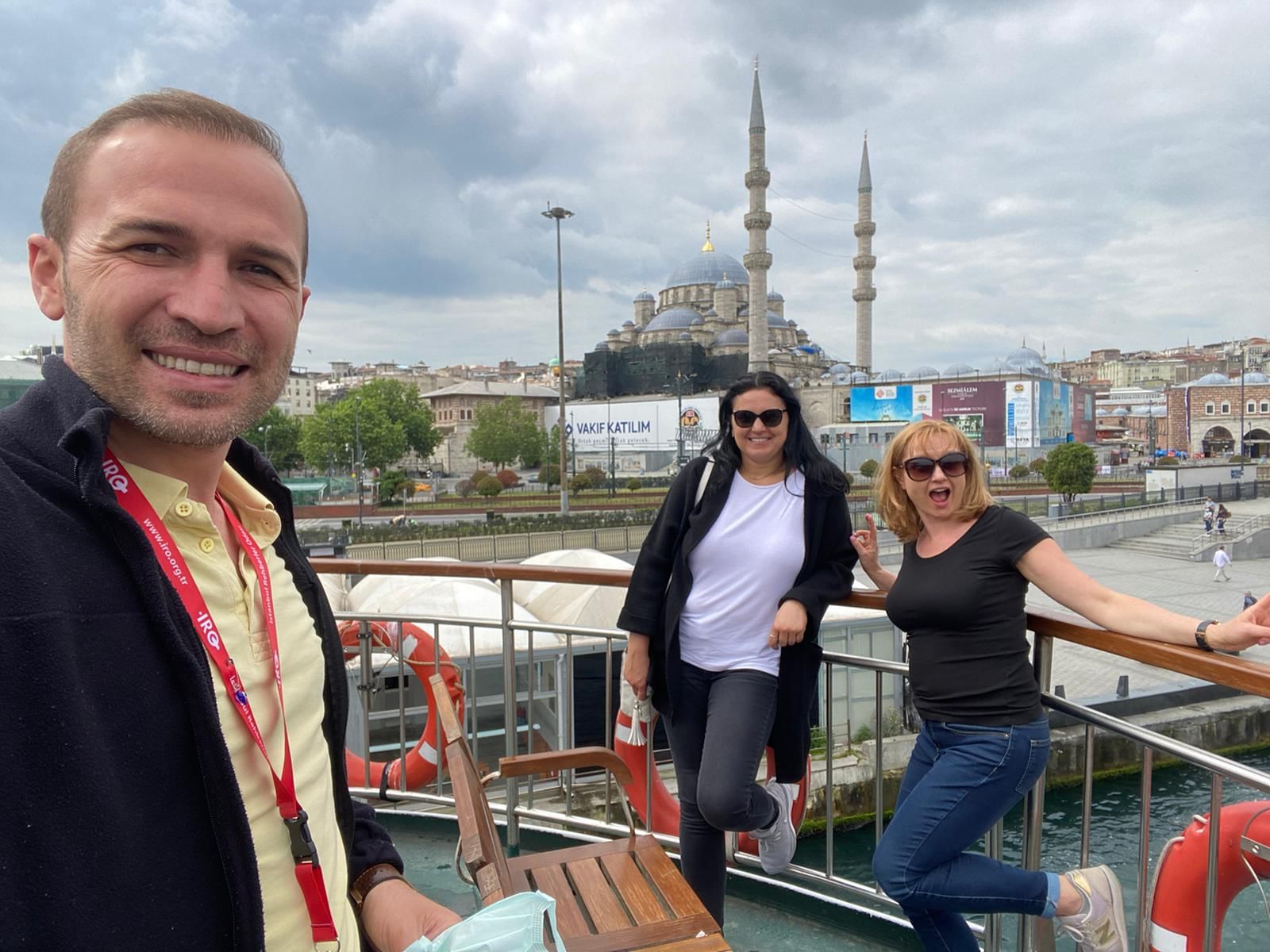 “A smiling tour guide speaking to a group of happy travelers outdoors, with historic architecture in the background.”