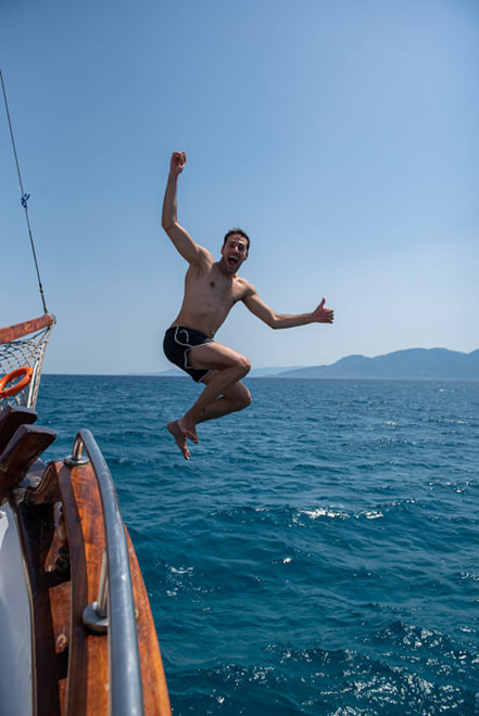 A guest jumping from the wooden boat into the sea