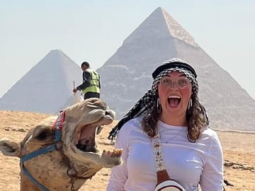 Camel Ride Fun at the Great Pyramid: Smiling tourist with camel near the Pyramid of Khafre in Giza, Egypt.