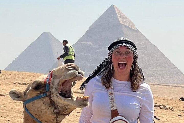Smiling tourist with camel near the Pyramid of Khafre in Giza, Egypt.