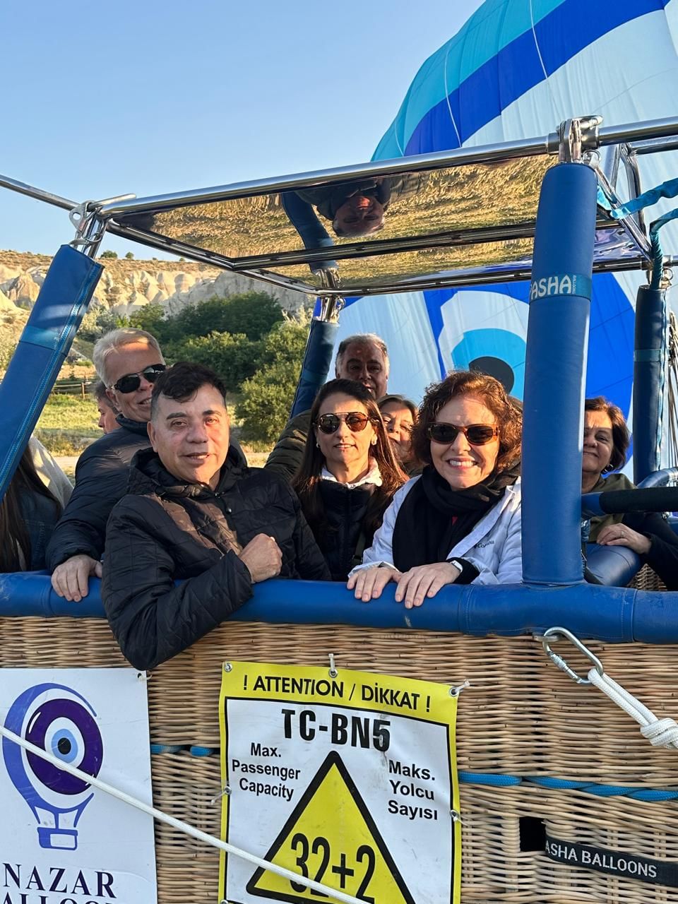 “Tour group smiling and enjoying a hot air balloon ride over the rocky valleys and unique landscape of Cappadocia.”