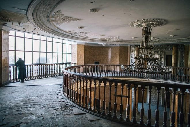 An elderly woman from the Abkhazian region of Georgia looks out the windows of a former hotel lobby in Tskaltubo, Georgia. The floors have been ripped up for firewood.