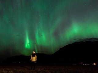 Woman looking at the Northern Lights in the Icelandic winter sky.